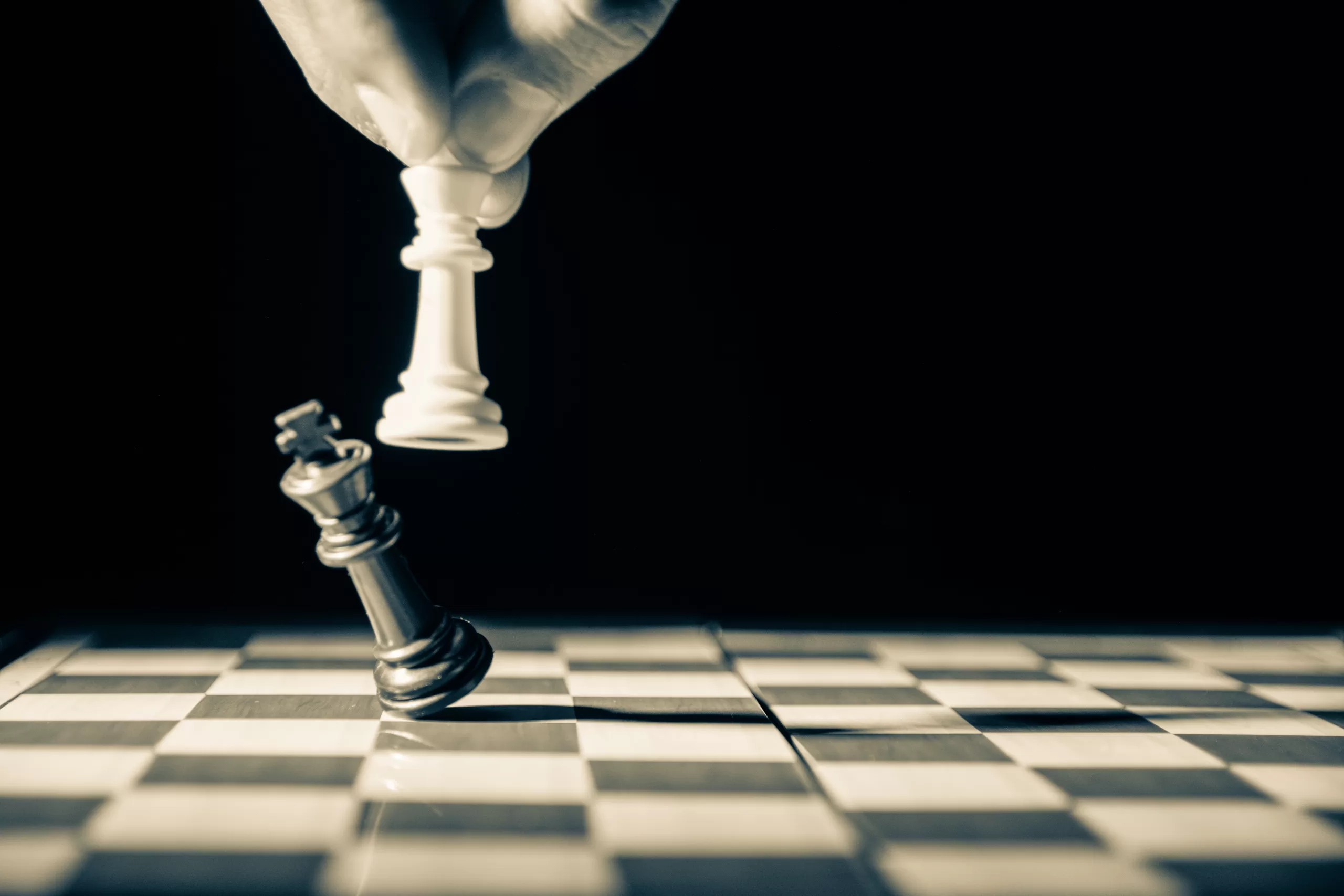 Closeup of a white king beating a black king in chess to symbolize beating your competition.